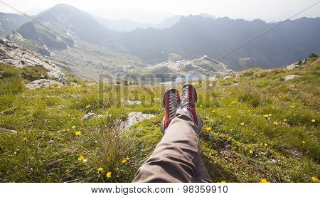 Legs of traveler sitting on a high mountain top in travel. Freedom concept