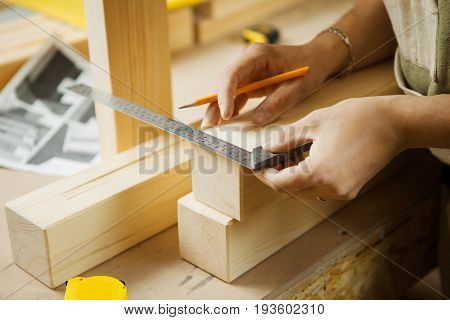 Craftsman measure wooden planks with help of ruler. Woodworker at workshop projecting details of processed material. Carpenter does measurements according to project