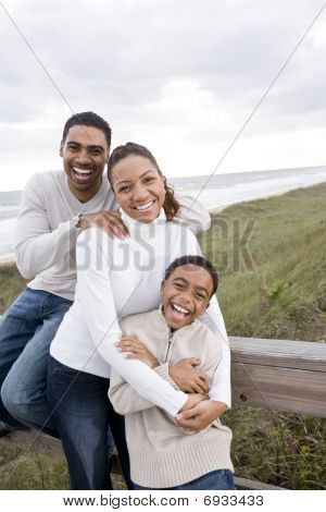 Afro-Amerikaanse familie lachen en knuffelen op strand