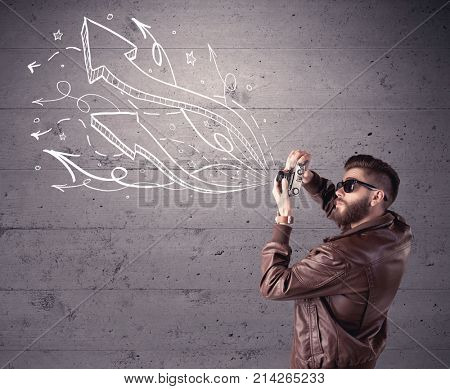 A hipster guy opening his point of view through looking a vintage camera concept with illustratied drawn arrows on urban wall