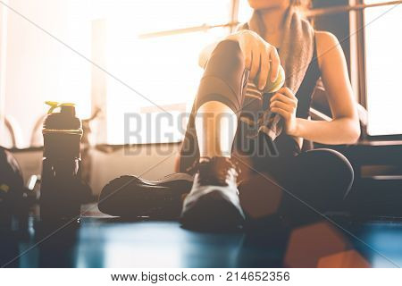 Sport Woman Sitting And Resting After Workout Or Exercise In Fitness Gym With Protein Shake Or Drink