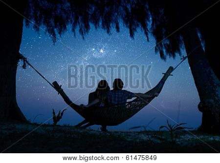 Couple relaxing in a hammock and enjoying starry sky