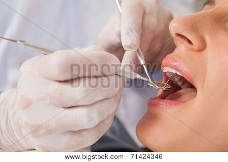 Dentist examining a patients teeth in the dentists chair at the dental clinic