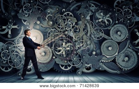 Young businessman fixing gears mechanism with wrench