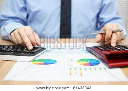 Financial Specialist Is Working With Calculator And Computer To Analyze A Lot Of Data On Financial R