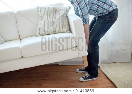 new home, real estate, moving and furniture concept - close up of male lifting up sofa or couch