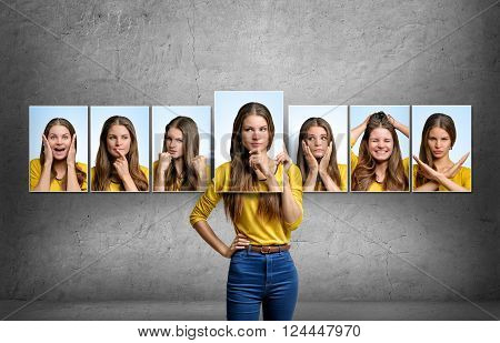 Young beautiful girl holds and changes her face portraits with different emotions.