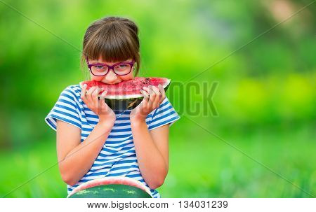 Child eating watermelon. Kids eat fruits in the garden. Pre teen girl in the garden holding a slice of water melon. happy girl kid eating watermelon. Girl kid with gasses and teeth braces.