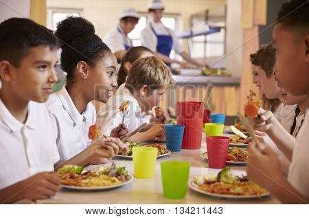 Primary school kids eat lunch in school cafeteria, close up