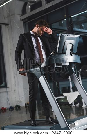 Tired Businessman Training On Treadmill In Sports Center