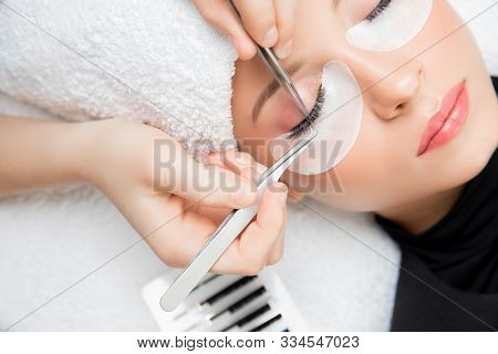 Eyelash Extension Procedure. Master Tweezers Fake Long Lashes Beautiful Female Eyes