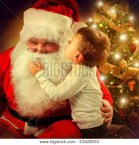 Santa Claus and Little Boy. Christmas Scene. Boy Telling Wish in Santa Claus's Ear in front of Christmas Tree 