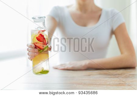 healthy eating, drinks, diet, detox and people concept - close up of woman with fruit water in glass bottle