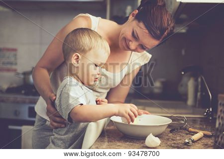 Mom with her 2 years old child cooking holiday pie in the kitchen to Mothers day, casual lifestyle photo series in real life interior