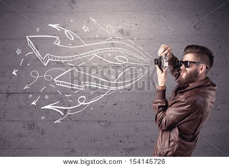 A hipster guy opening his point of view through looking a vintage camera concept with illustratied drawn arrows on urban wall