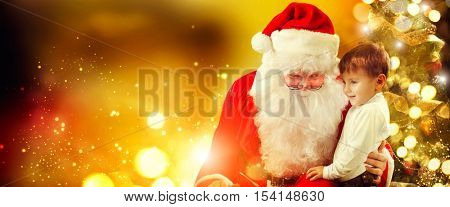 Santa Claus and Little Boy. Christmas Scene. Boy Telling Wish in Santa Claus's Ear in front of Christmas Tree. Santa listening to a little boy's wishes