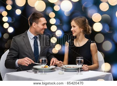 restaurant, couple and holiday concept - smiling couple eating main course at restaurant