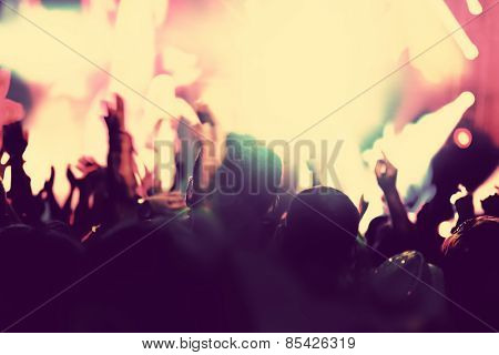 Concert, disco party. People with hands up having fun in night club lights. Vintage mood