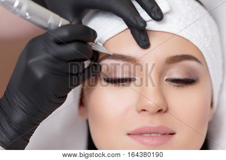 Permanent makeup. Permanent tattooing of eyebrows. Cosmetologist applying permanent make up on eyebrows- eyebrow tattoo