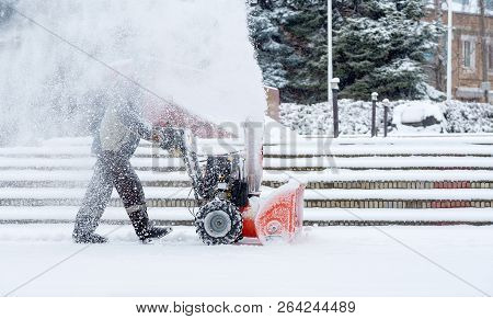 Snow-removal Work With A Snow Blower. Man Removing Snow. Heavy Precipitation And Snow Piles