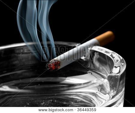 Closeup of cigarette on ashtray with a beautiful wisp of smoke