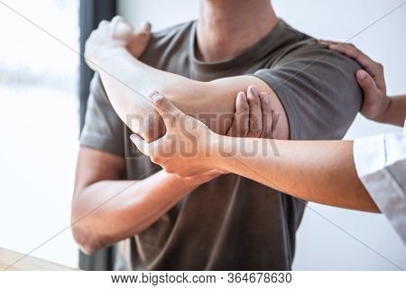 Female Physiotherapist Working Examining Treating Injured Arm Of Athlete Male Patient, Stretching An