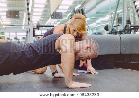 Personal trainer encouraging muscle man in push ups training