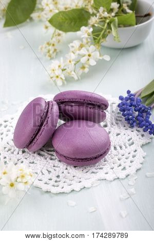 Three purple macaroons cookies and flowers on the table