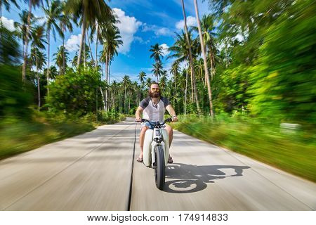 bearded man in thailand riding vintage motorbike with motion blur