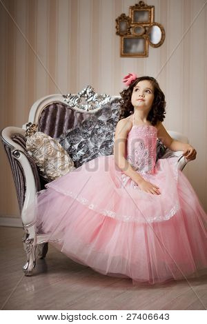 A beautiful girl, a child on a chair in a nice dress