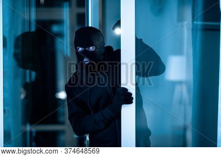 Burglary Concept. Watchful Thief Lurking Into Residential Building Through Open Front Door, Entering