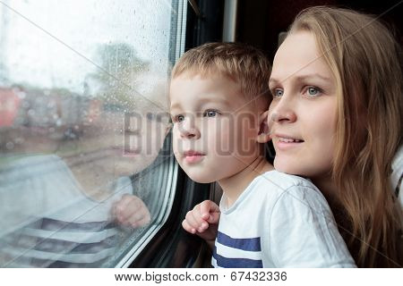 Mother and son looking through a train window