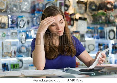 Worried Woman Checking Bills And Invoices In Computer Shop