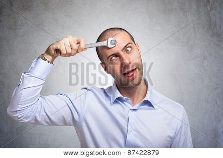 Funny man using a wrench to fix his brain