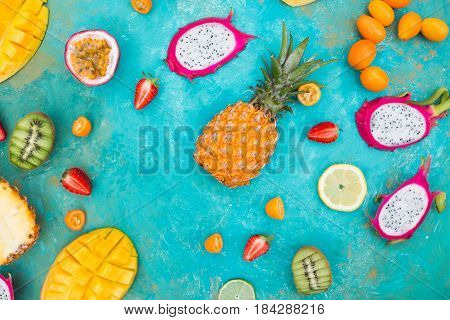 Exotic fruits. Mango. Papaya. A pineapple. Kiwi. Pitahaya. Kumhvat. Copyspase. Fresh fruits. Exotic fruits on a the turquoise background. Blueberry. Strawberry. Physalis. Tamarind. Fruit slices. Lime. Lemon. Orange.