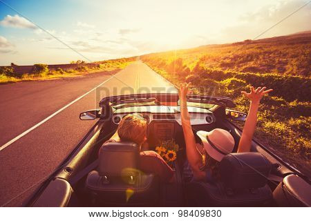 Happy Young Couple Driving Along Country Road in Convertible at Sunset. Freedom Adventure Road Trip