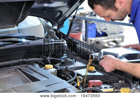 Car mechanic changing oil - model and oil motion blurred.