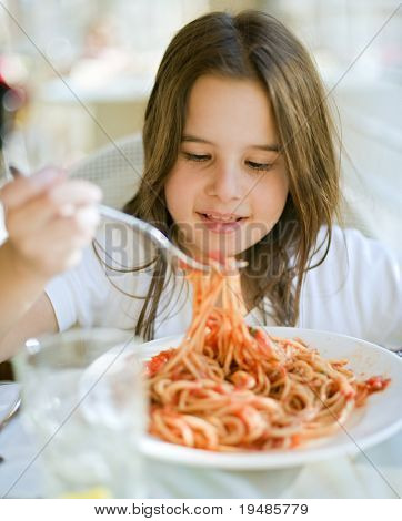 young girl eating spaghetti in restaurant