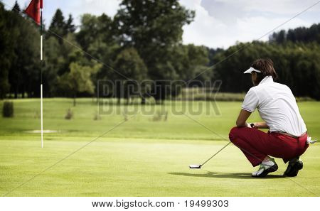 Jogador de golfe feminino com o taco de cócoras para analisar o verde no campo de golfe.