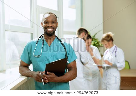 Healthcare People Group. Professional African American Male Doctor Posing At Hospital Office Or Clin