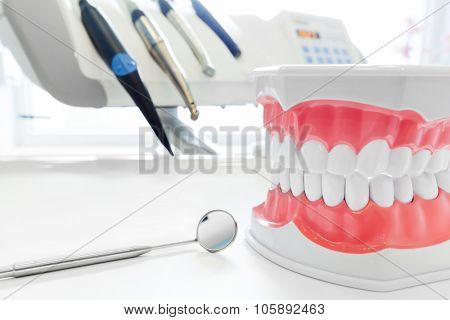 Clean teeth denture, dental jaw model, mirror and dentistry instruments in dentist's office. 