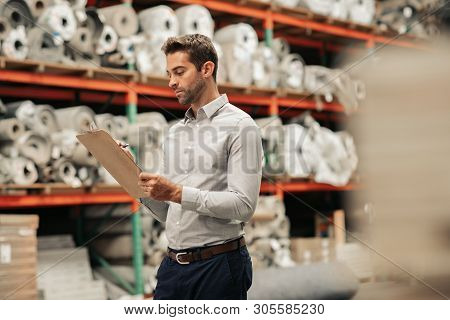 Manager Doing An Inventory Check On A Warehouse Floor