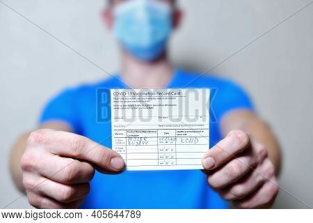 Male Is Holding A Vaccination Record Card And Corona Virus Vaccine Vials. Passport Of Immunity To Th