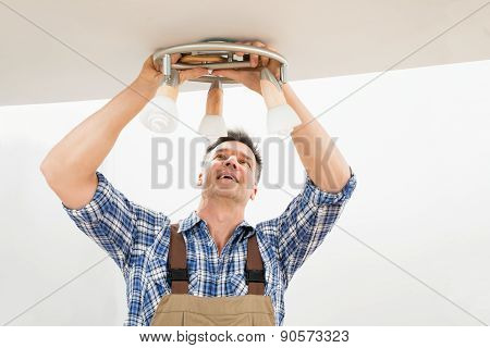 Technician Fixing Light On Ceiling