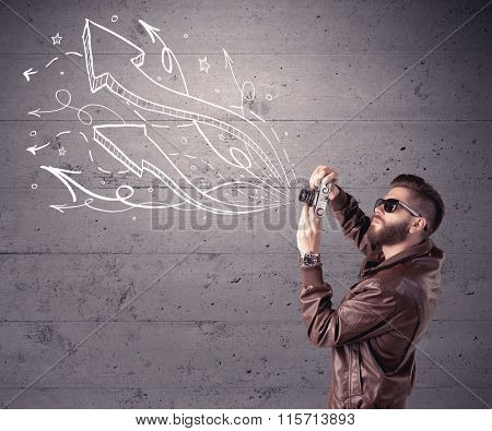 A hipster guy opening his point of view through looking a vintage camera concept with illustratied drawn arrows on urban wall