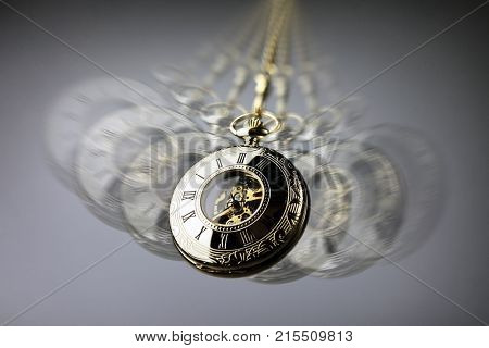 Hypnotism concept, gold pocket watch swinging used in hypnosis treatment