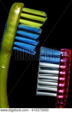 Close Up Isolated Image Of Two Toothbrushes Facing Each Other. The Taller Yellow, Blue One Belongs T