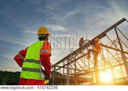 Engineer working on building site, Engineer technician watching warehouse steel roof structure , Engineer technician Looking Up and Analyzing an Unfinished Construction Project.