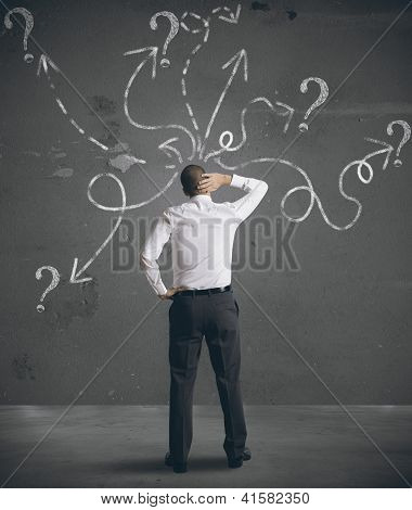 Businessman Looking At Arrows Pointed In Different Directions