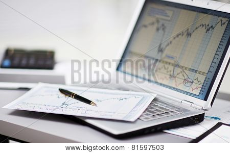 Businessman analyzing investment charts with laptop.